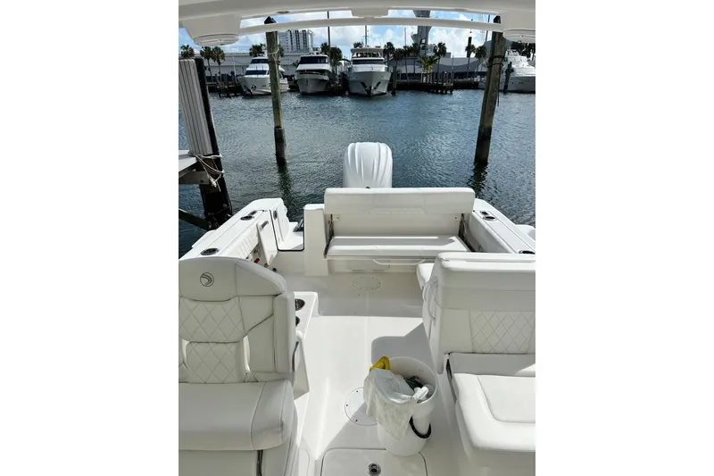 Slide: The Image of 2023 Edgewater 248CX Crossover boat interior with white seating, docked at marina. - 9
