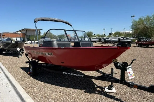 The Image of 2026 Tracker Pro Guide V-16 WT boat in red, parked on a trailer in a sunny outdoor setting. - 0
