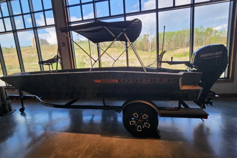 The Image of 2026 Tracker Grizzly 1756 T Marsh boat with Mercury engine, displayed indoors. - 0