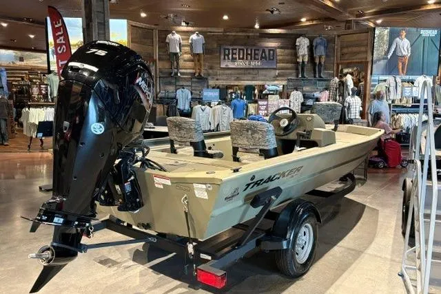 The Image of 2026 Tracker Grizzly 1754 SC boat displayed indoors, featuring a Mercury outboard motor. - 0