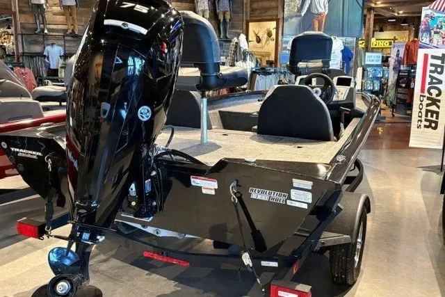 The Image of 2026 Tracker Pro Team 175 boat displayed indoors, featuring a sleek black exterior and powerful engine. - 0