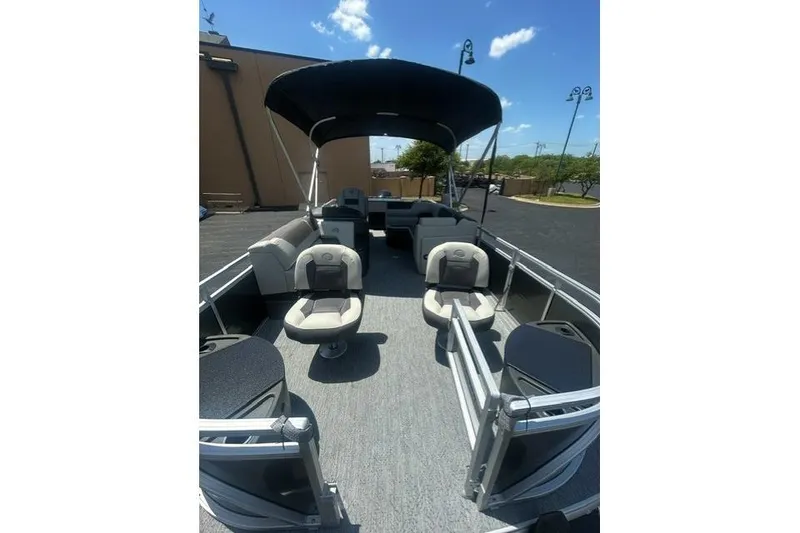Slide: The Image of 2026 Sun Tracker Fishin' Barge 20 DLX pontoon boat with seating and canopy under blue sky. - 4