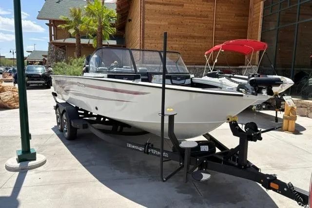 Slide: The Image of 2026 Ranger VX1988 WT boat on trailer, displayed outdoors near wooden building. - 1