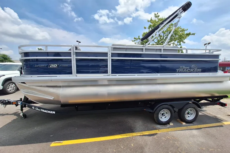 Slide: The Image of 2026 Sun Tracker SportFish 20 DLX pontoon boat on trailer under a clear sky. - 2