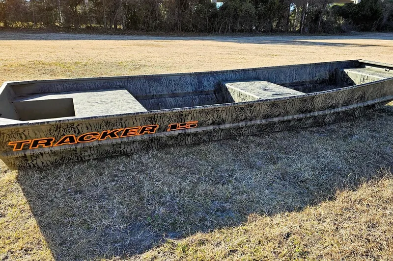 The Image of 2026 Tracker Grizzly 15 Jon boat on grassy field, showcasing rugged design. - 0