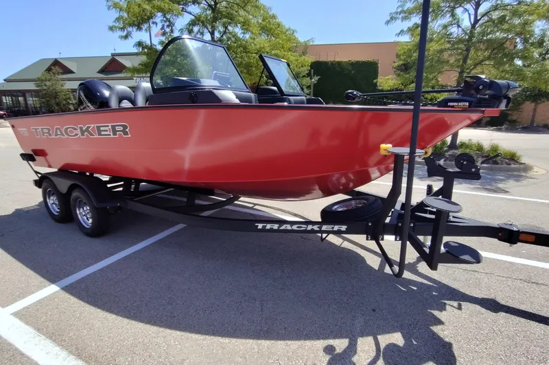 The Image of 2026 Tracker Targa V-18 Combo boat on trailer, parked outdoors, vibrant red color. - 0