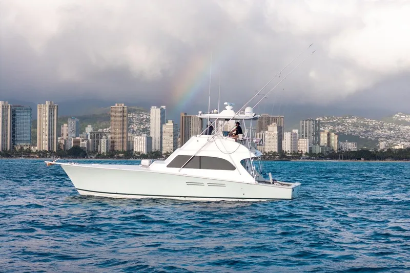 Slide: The Image of A 1998 Post 50 yacht cruising near a city skyline with a rainbow in the background. - 21