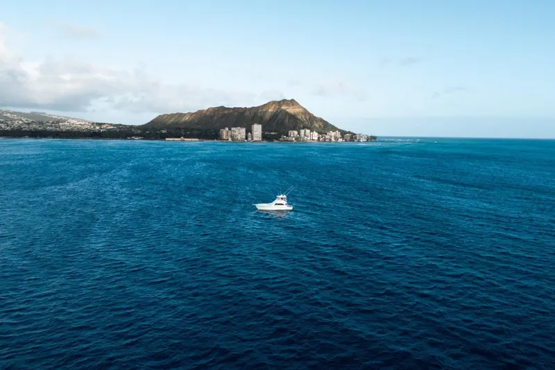 Slide: The Image of A boat on the ocean with a mountainous coastline in the background. - 22