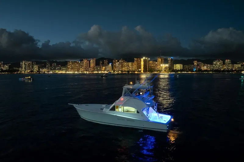 Slide: The Image of A 1998 Post 50 yacht illuminated at night, with a city skyline in the background. - 12