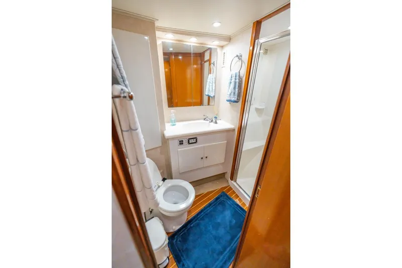 Slide: The Image of Compact yacht bathroom with shower, sink, and toilet; features wooden accents and blue rug. - 20