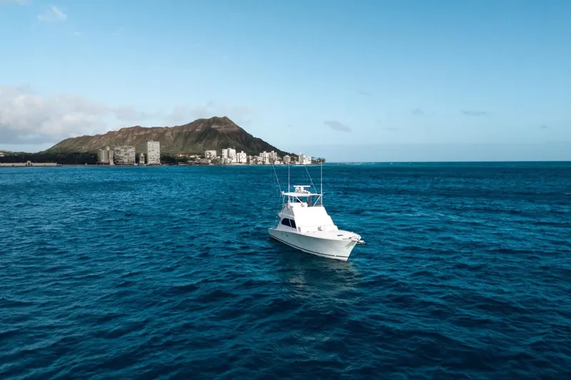 Slide: The Image of A 1998 Post 50 yacht on blue ocean with mountain and cityscape background. - 29