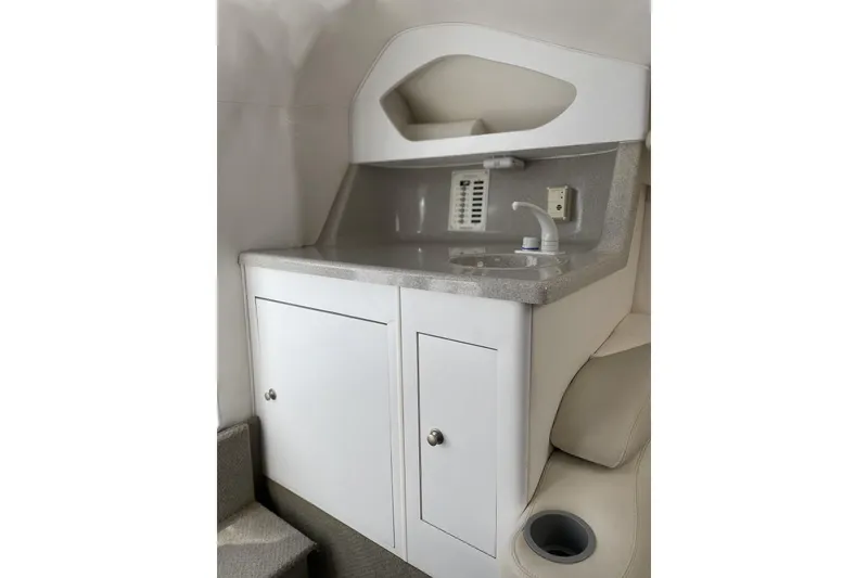 Slide: The Image of Interior of a 2000 Baja 33 Outlaw boat featuring a compact sink and storage cabinets. - 6