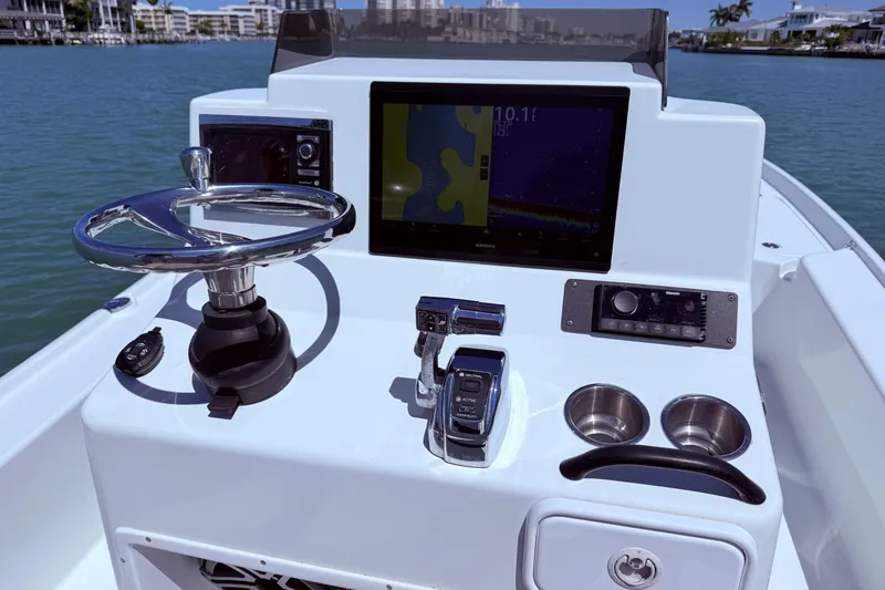 Slide: The Image of 2014 Yellowfin 24 Bay boat dashboard with steering wheel, navigation screen, and controls. - 2