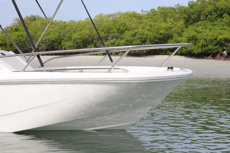 Slide: The Image of 2027 Boston Whaler 130 Super Sport boat on calm water near lush shoreline. - 7