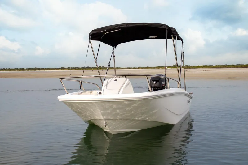 Slide: The Image of 2027 Boston Whaler 130 Super Sport boat on calm water with canopy. - 9