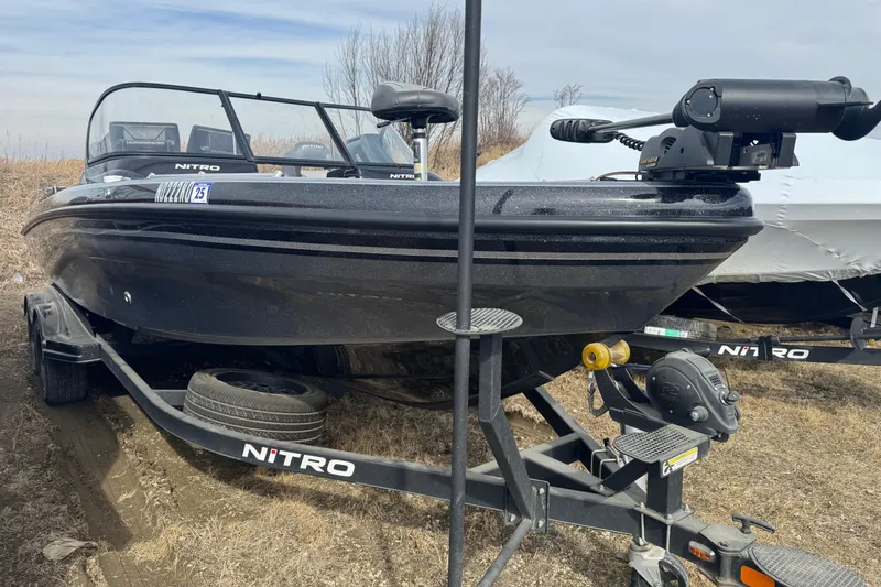 Slide: The Image of 2018 Nitro ZV21 boat on trailer, parked outdoors, with trolling motor attached. - 2