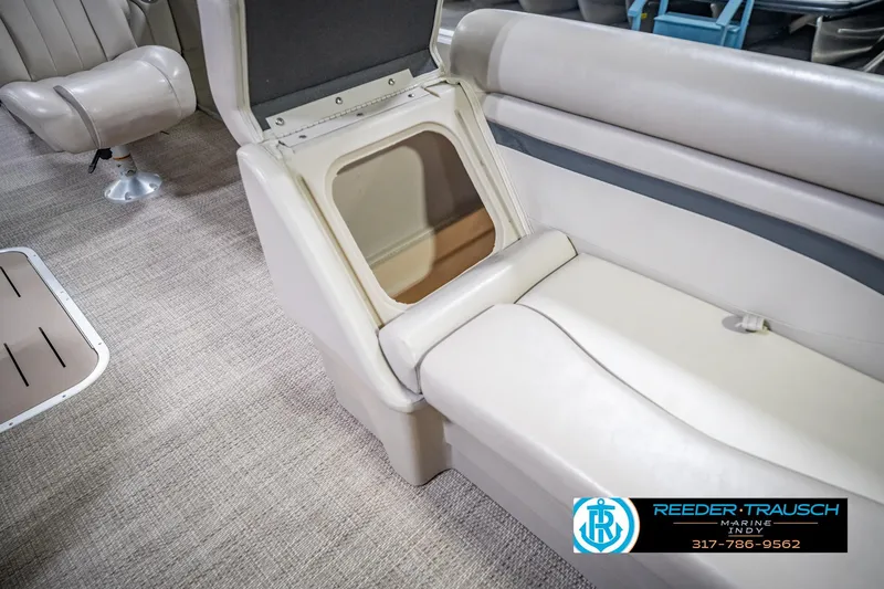 Slide: The Image of 2018 Bennington 23 SSRX boat interior with open storage compartment and beige seating. - 24