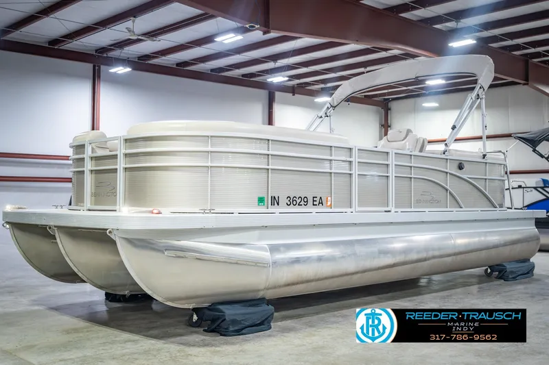 Slide: The Image of 2018 Bennington 23 SSRX pontoon boat in indoor showroom, Reeder-Trausch Marine logo visible. - 3