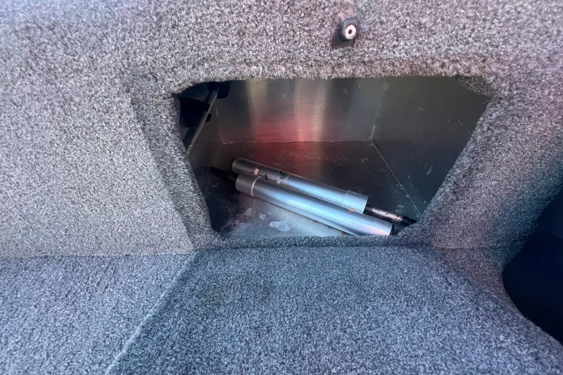 Slide: The Image of Storage compartment in 2023 Tracker Bass Tracker Classic XL boat, featuring carpeted interior and metal rods. - 73