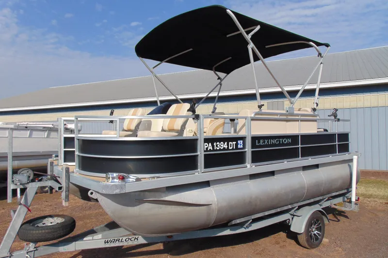 The Image of 2017 Lexington 317 pontoon boat on trailer with canopy, parked outdoors. - 1