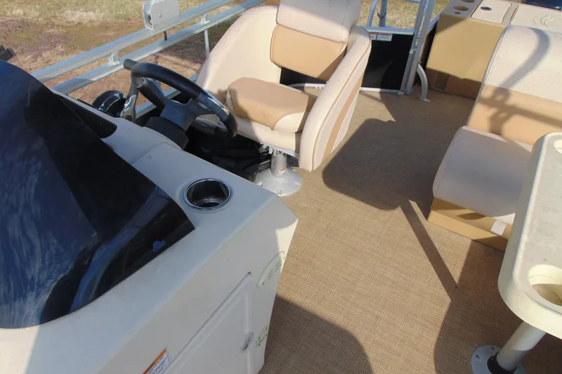 Slide: The Image of 2017 Lexington 317 pontoon boat interior with steering wheel and beige seating. - 10