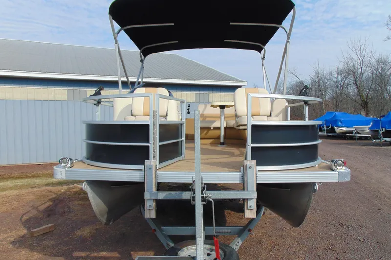 Slide: The Image of 2017 Lexington 317 pontoon boat on trailer, beige seating, black exterior, under blue sky. - 6