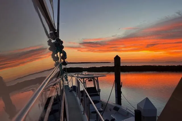The Image of 1987 Californian 45 Motor Yacht at sunset, reflecting vibrant orange and pink sky over calm water. - 0