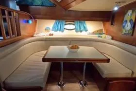 Slide: The Image of 1987 Californian 45 Motor Yacht interior with cozy dining area and blue curtains. - 38