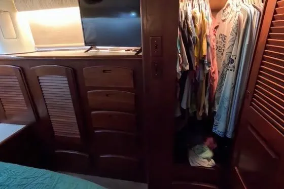 Slide: The Image of 1987 Californian 45 Motor Yacht interior with closet and TV, showcasing wooden cabinetry. - 44