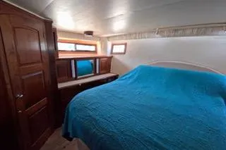 Slide: The Image of 1987 Californian 45 Motor Yacht bedroom with blue bedding and wooden cabinetry. - 48