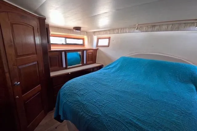 Slide: The Image of 1987 Californian 45 Motor Yacht bedroom with blue bedspread and wooden cabinetry. - 50