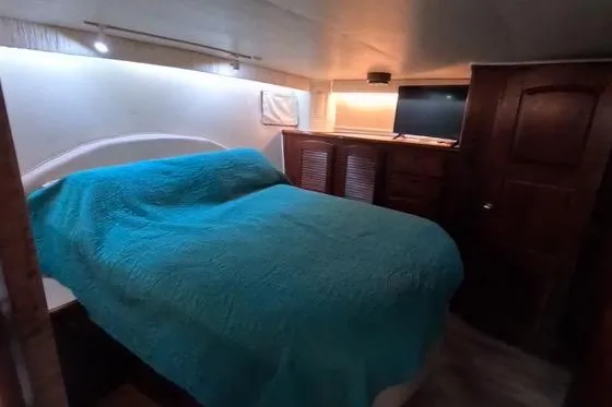 Slide: The Image of 1987 Californian 45 Motor Yacht bedroom with turquoise bedding and wooden cabinetry. - 52