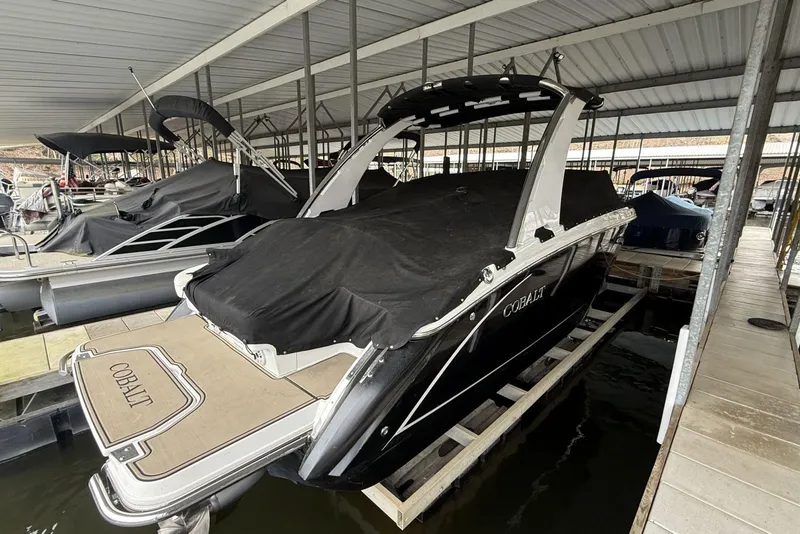 Slide: The Image of 2014 Cobalt R5 boat docked under a covered marina, partially covered with a black tarp. - 3