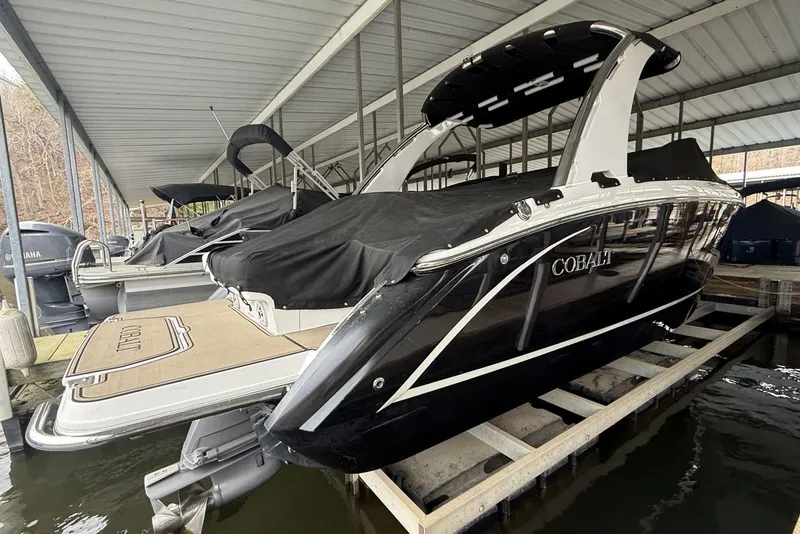 Slide: The Image of 2014 Cobalt R5 boat docked under a covered marina, partially covered with a black tarp. - 4