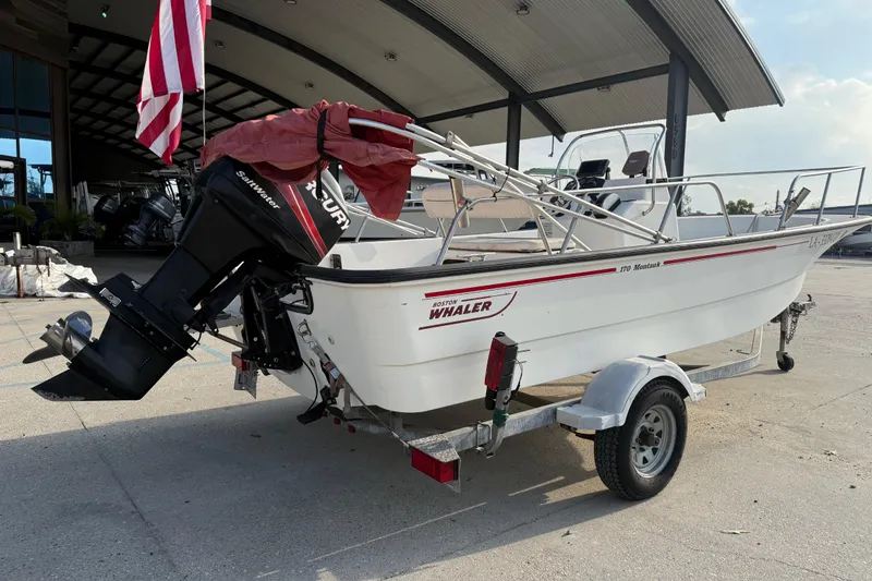 Slide: The Image of 2005 Boston Whaler 17 Montauk boat on trailer, parked outdoors with American flag. - 2