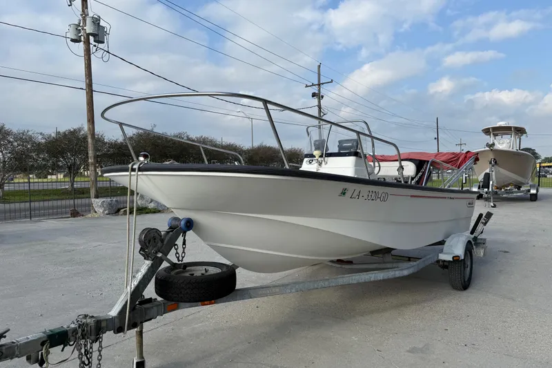 Slide: The Image of 2005 Boston Whaler 17 Montauk boat on trailer, parked outdoors under cloudy sky. - 4