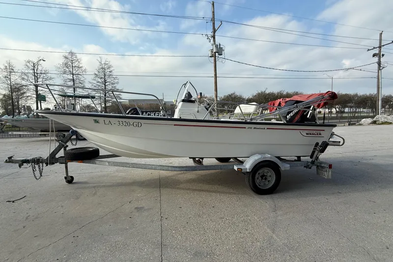 Slide: The Image of 2005 Boston Whaler 17 Montauk boat on trailer, parked outdoors under a cloudy sky. - 5