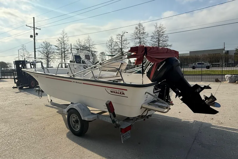 Slide: The Image of 2005 Boston Whaler 17 Montauk boat on trailer with outboard motor in sunny outdoor setting. - 6