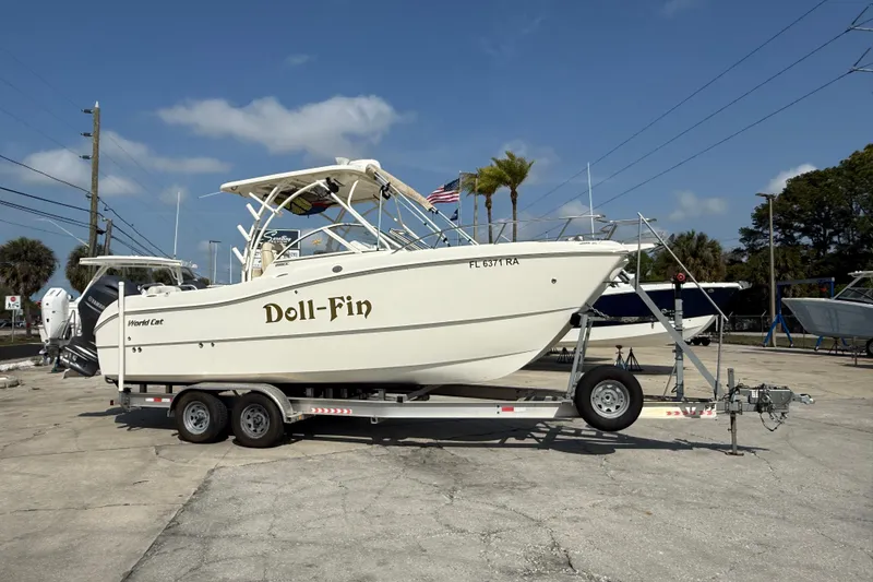 Slide: The Image of 2016 World Cat 255 DC boat named "Doll-Fin" on a trailer in a marina. - 2