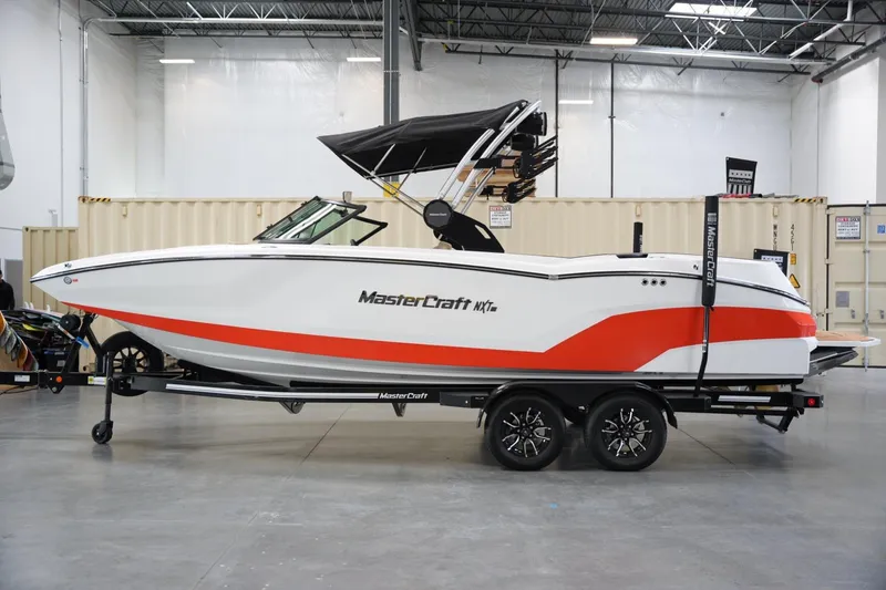 Slide: The Image of 2025 MasterCraft NXT24 boat in a showroom, featuring sleek design and vibrant red accents. - 1