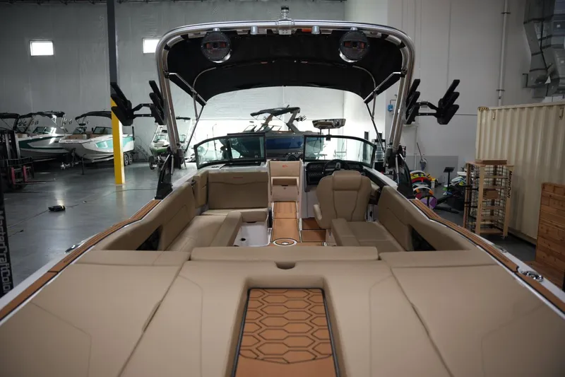 Slide: The Image of 2025 MasterCraft NXT24 boat interior with tan seating in a showroom. - 16