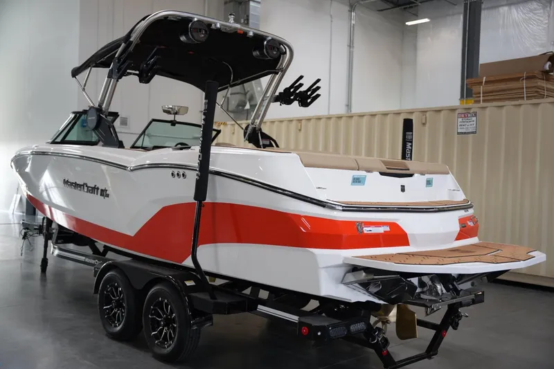 Slide: The Image of 2025 MasterCraft NXT24 boat in a showroom, featuring a sleek red and white design. - 2