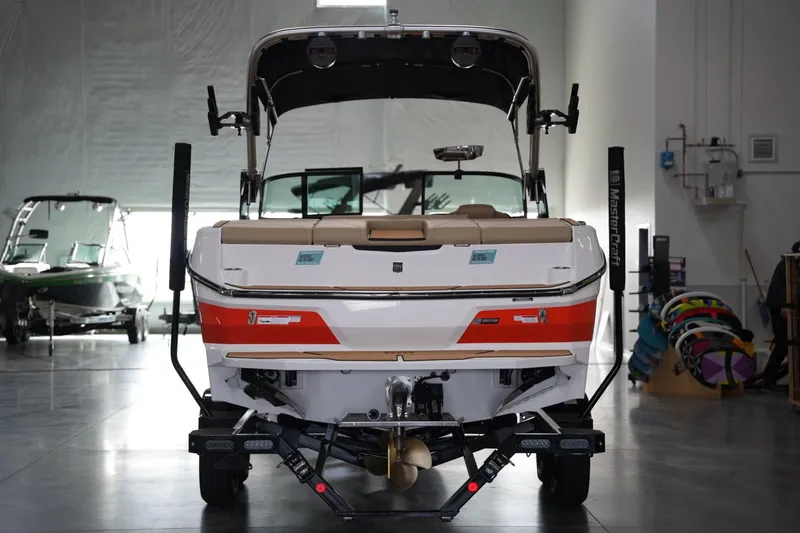 Slide: The Image of 2025 MasterCraft NXT24 boat in showroom, rear view with vibrant orange accents. - 3