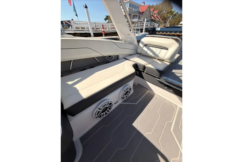Slide: The Image of 2019 Regal LS4 boat interior with cushioned seating and speakers, docked near a marina. - 14