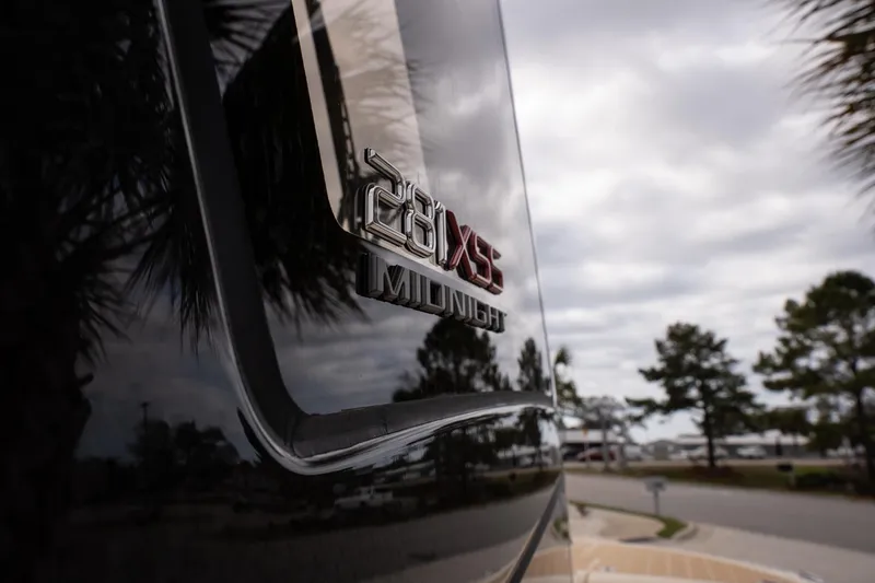 Slide: The Image of 2026 Scout 281 XSS boat with "Midnight" emblem, reflecting cloudy sky and trees. - 21