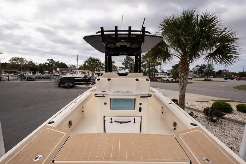 Slide: The Image of 2026 Scout 281 XSS boat with spacious deck, parked near palm trees under cloudy sky. - 6