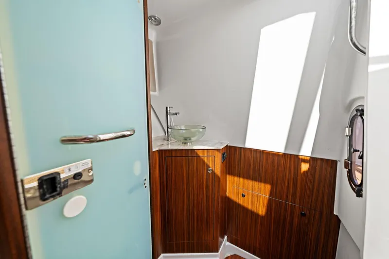 Slide: The Image of Interior of 2022 Pursuit DC 365 Dual Console boat, featuring a modern bathroom with wood accents. - 36