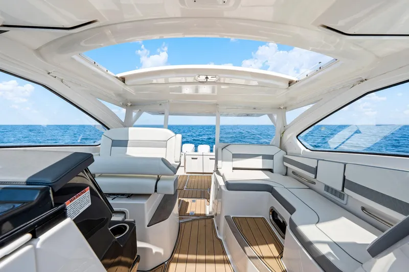 Slide: The Image of 2022 Pursuit DC 365 Dual Console boat interior with ocean view, featuring luxurious seating. - 57