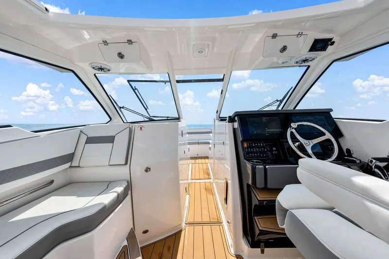 Slide: The Image of 2022 Pursuit DC 365 Dual Console interior with modern helm and seating, under clear skies. - 60