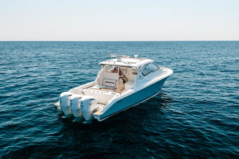 Slide: The Image of 2022 Pursuit DC 365 Dual Console boat on open sea, featuring triple outboard engines. - 8
